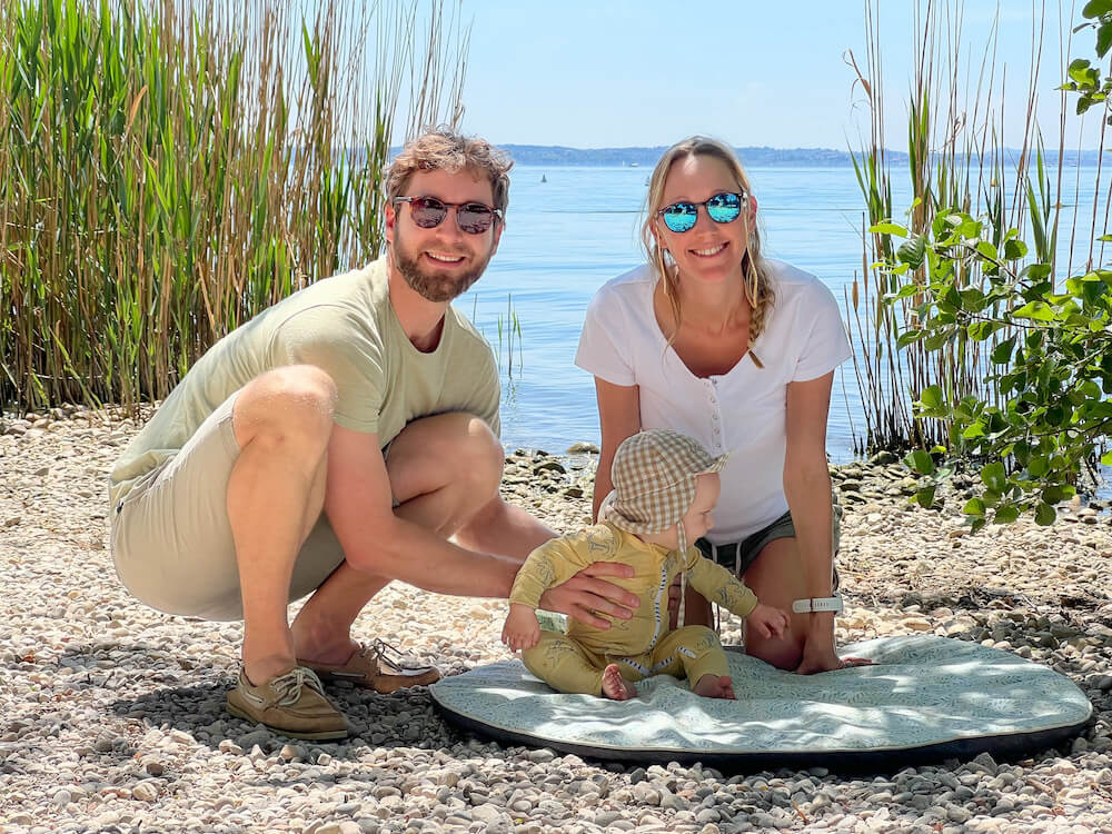 A couple and baby on a travel mat during a family holiday