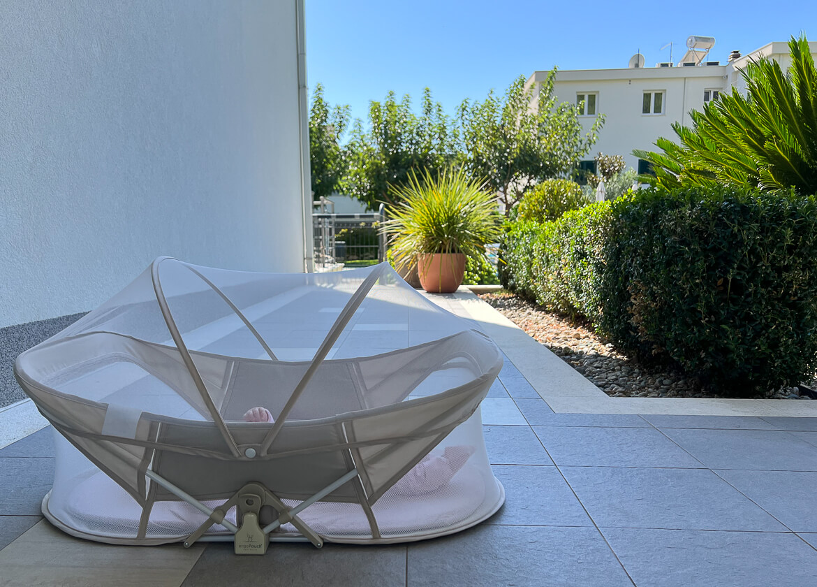 A baby sleeping in a travel bassinet