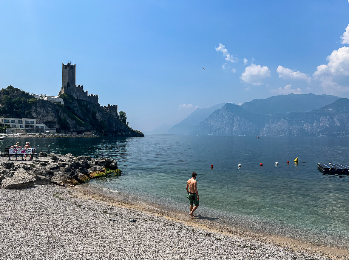 The best beach in Lake Garda with a castle and mountain backdrop