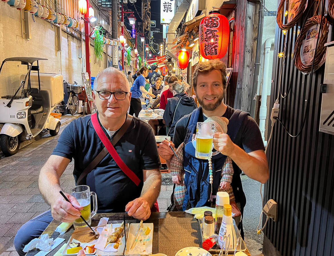 Two men and a baby enjoying dinner at Dinner at Omoide Yokocho in Tokyo