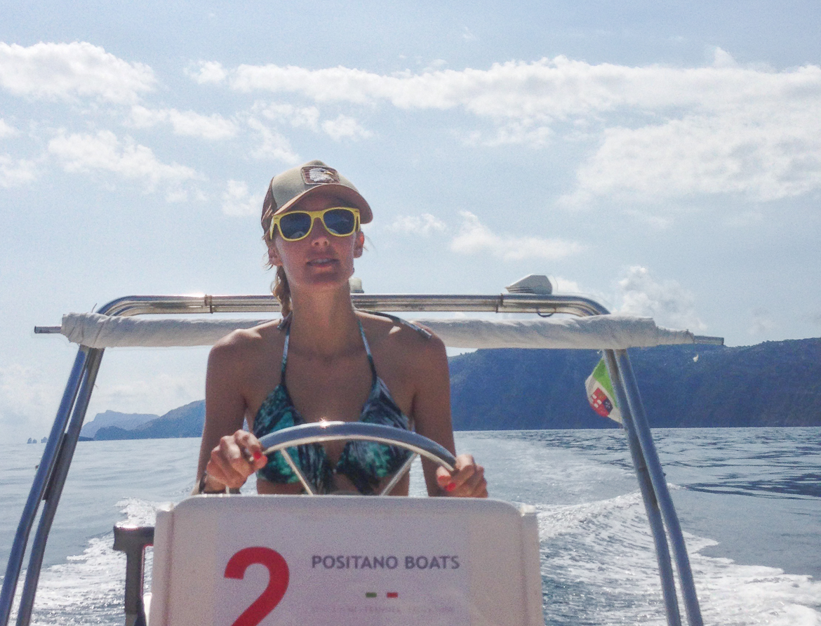 A woman driving a boat on the Amalfi Coast