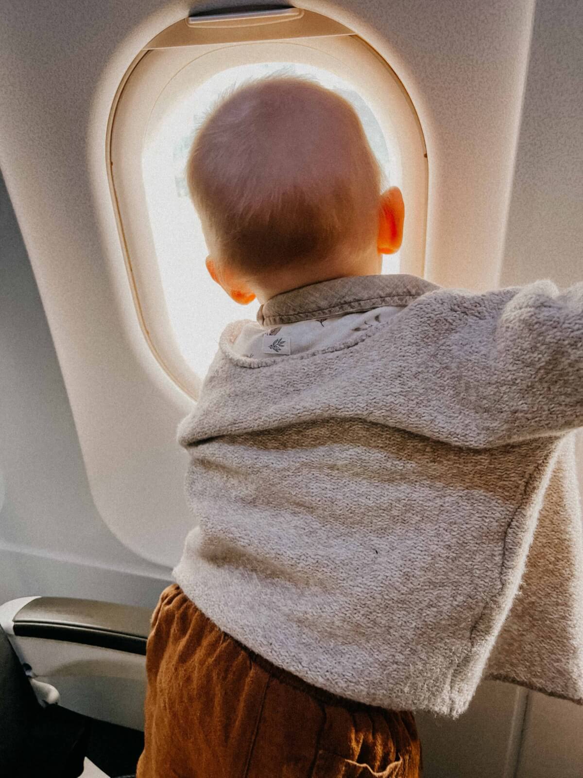 A baby looking out the window of an aeroplane