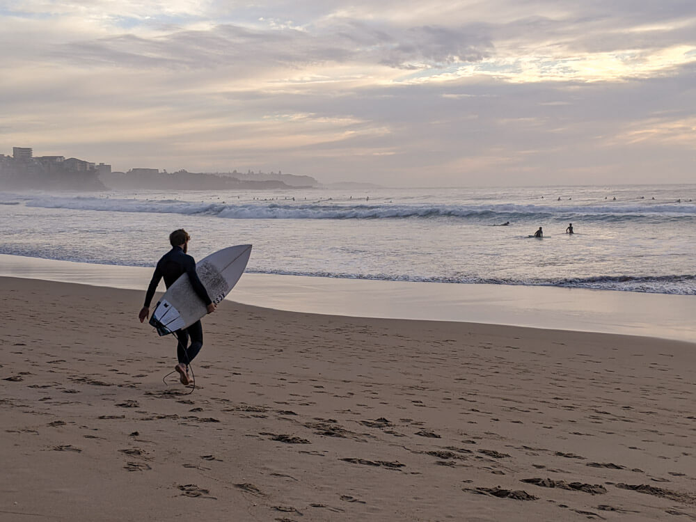 A surfer walking to the waves in Manly