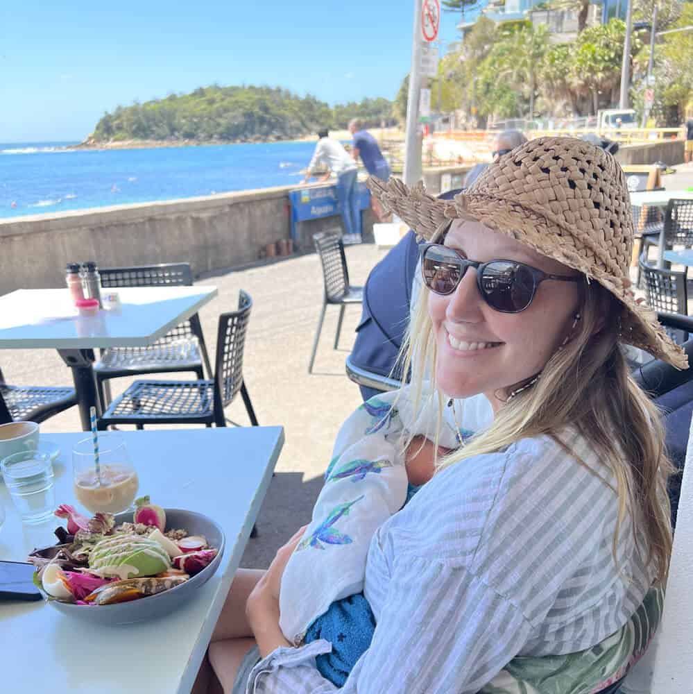 A woman enjoying brunch overlooking the water at a cafe in Manly