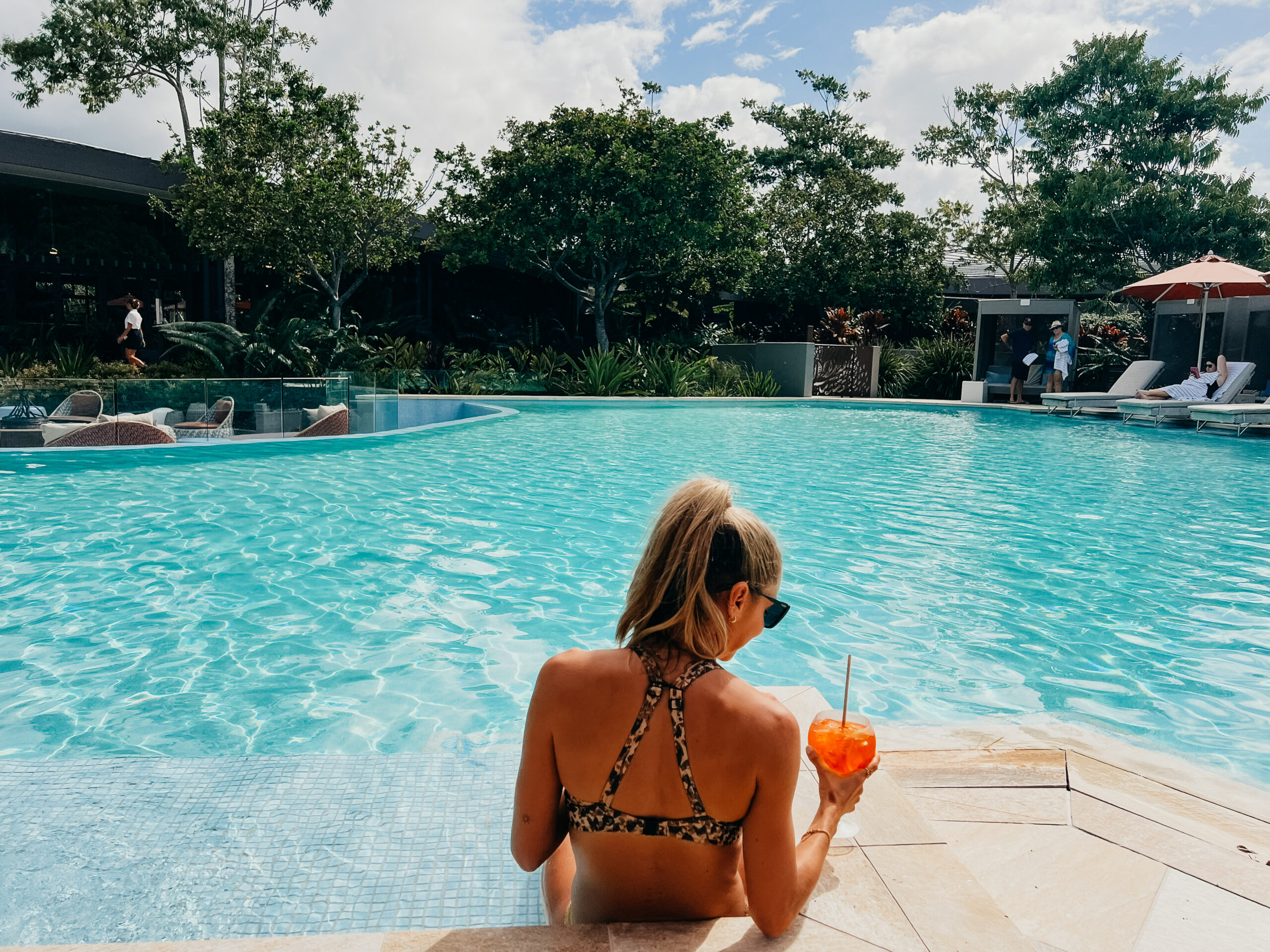 A woman enjoying a cocktail at the lagoon pool