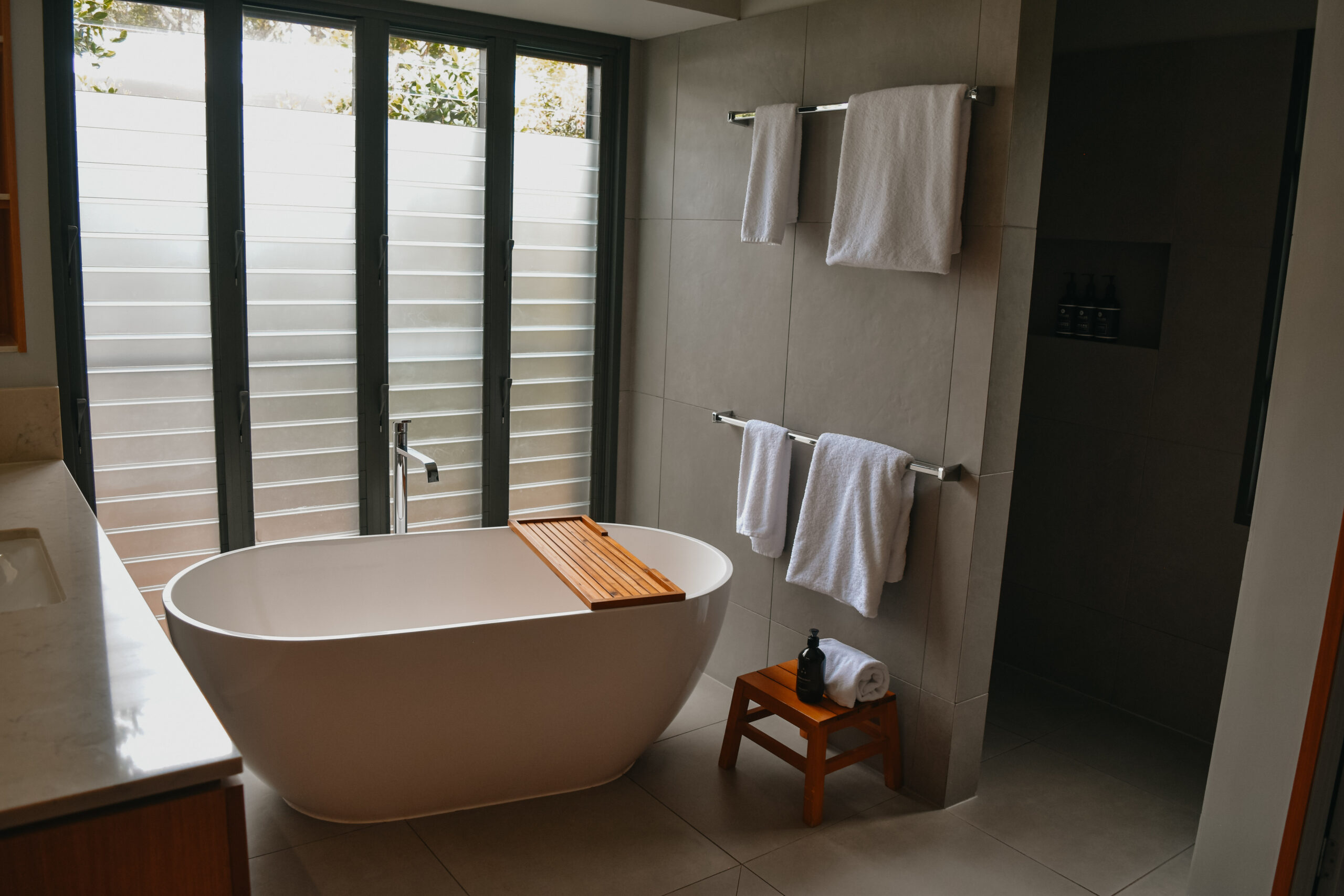 A luxurious bathroom featuring a deep, freestanding oval bathtub positioned next to a large window.