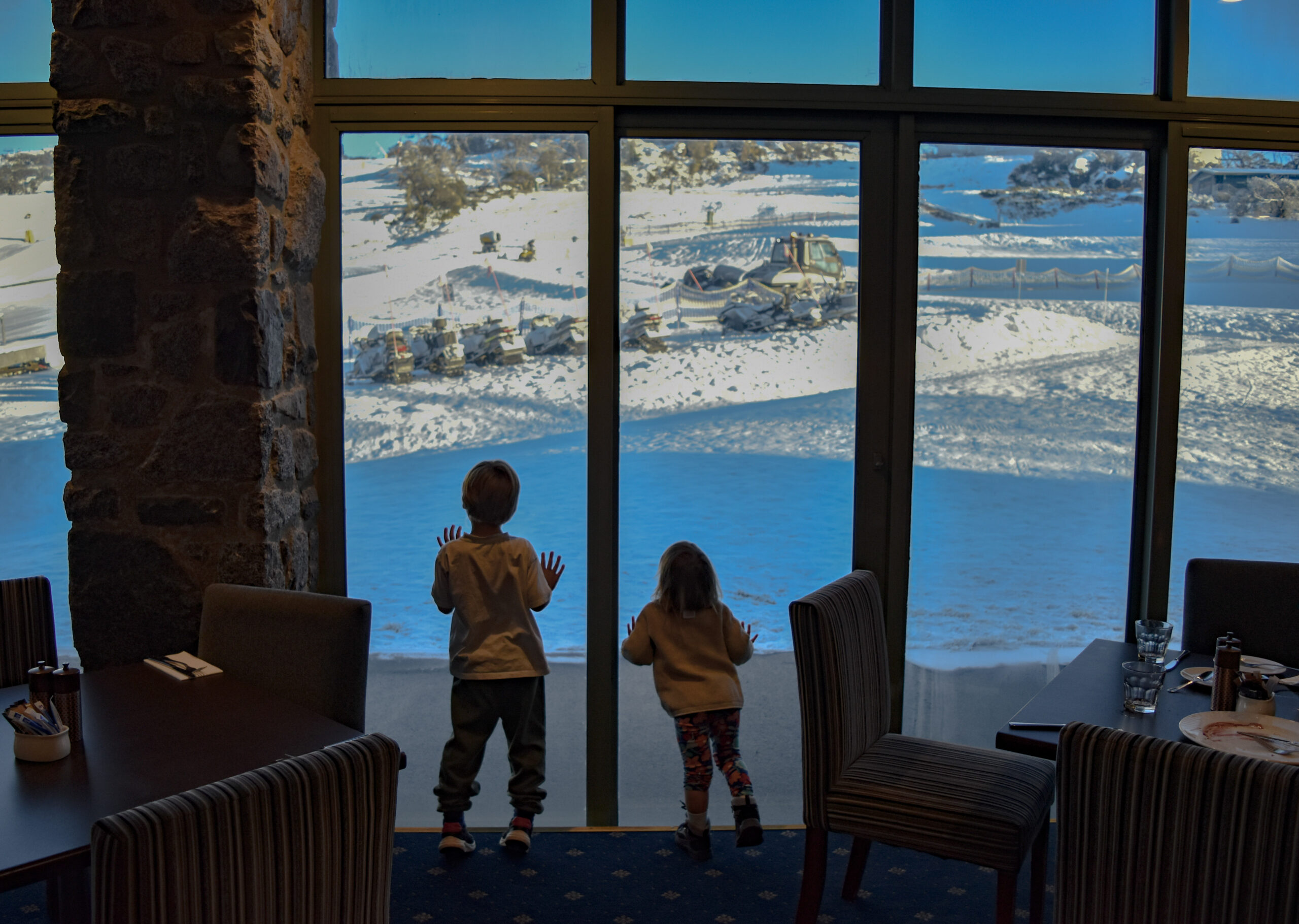 Two children looking out the window at the snow